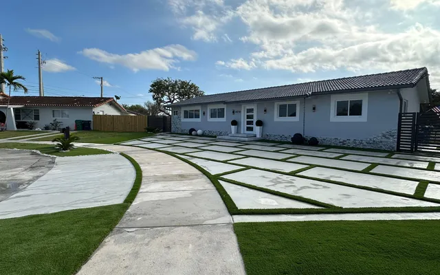 Expansive open backyard turf lawn bordered by wood rail fencing and mature landscaping