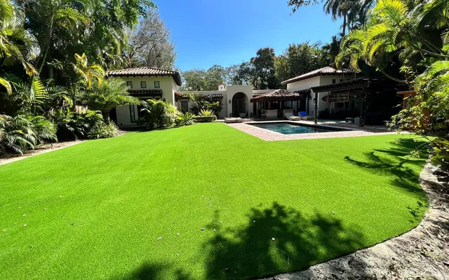 Lush, evenly green artificial turf backyard lawn under bright South Florida sun