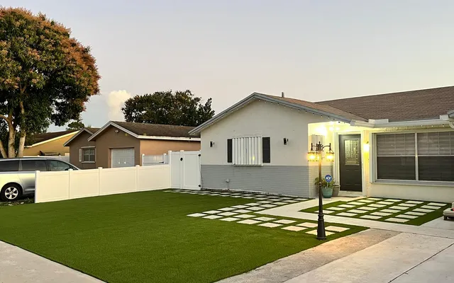 Well-maintained artificial turf front lawn with clean edging along a paver walkway