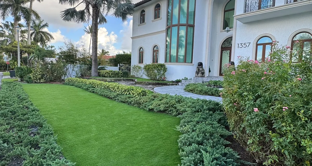 Side-yard artificial lawn running past a paver walkway toward a screened pool enclosure