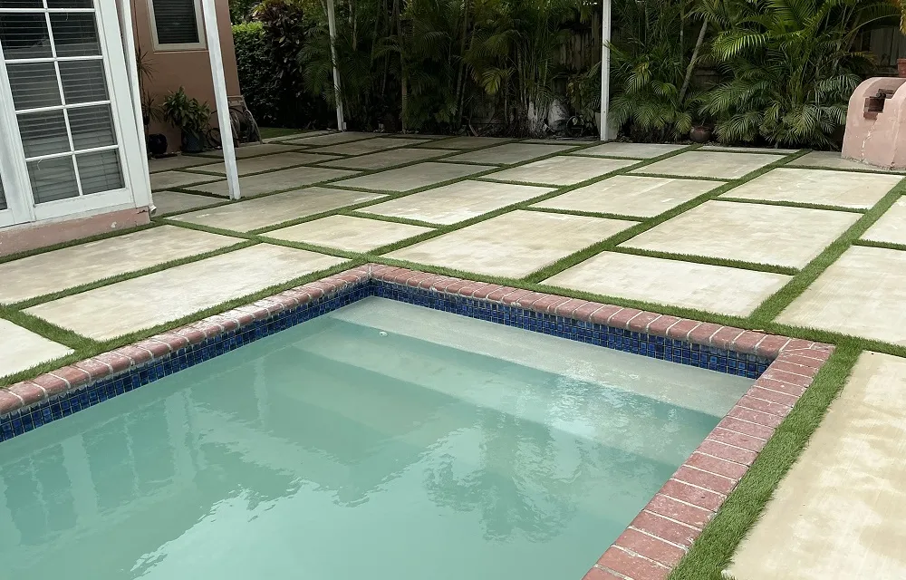 Compact fenced side yard with a neat artificial turf lawn bordered by a low garden wall