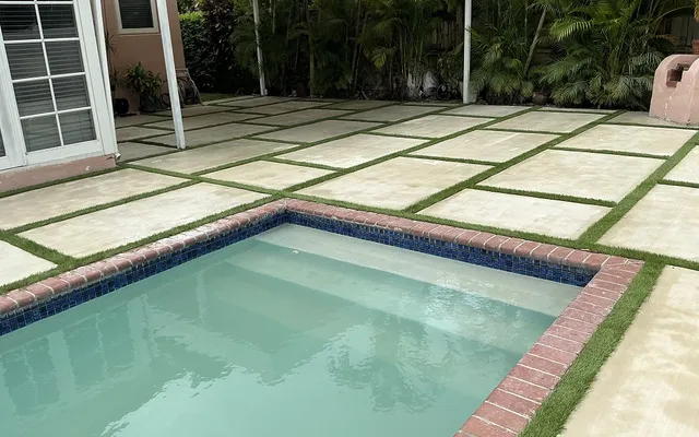 Compact fenced side yard with a neat artificial turf lawn bordered by a low garden wall